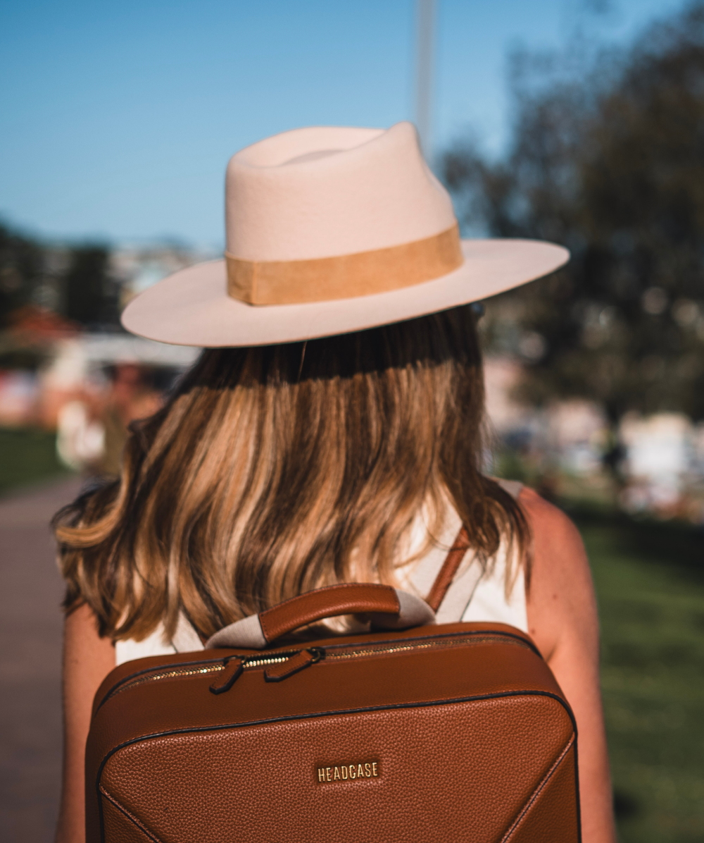 headcase backpack bondi bombshell tobacco brown backpack on model with hat while walking outside