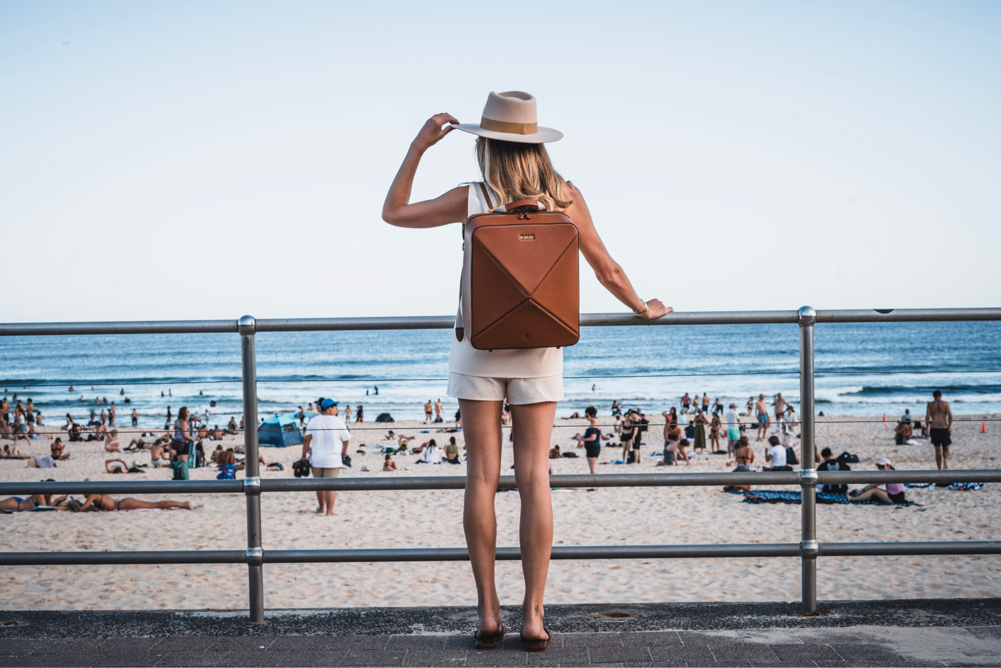 traveler posing with headcase backpack bondi bombshell tobacco brown backpack by the beach