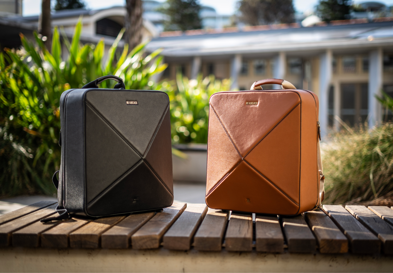 headcase backpack bondi byron boho noir black backpack and bombshell tobacco brown backpack facing each other outdoors